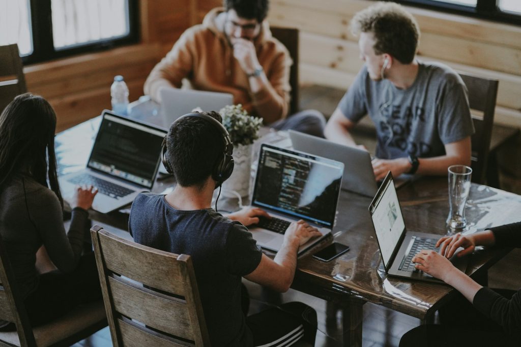Equipe reunida em torno de uma mesa com notebooks